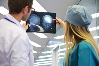 A surgeon and a nurse reviewing x-rays of the human head